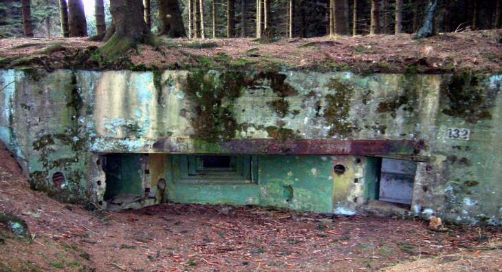 Alter Bunker aus Beton im Wald mit Verwitterungsspuren und Moosbewuchs