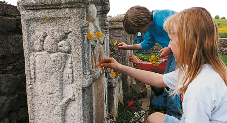 Steindenkmal mit Blumen und Kindern